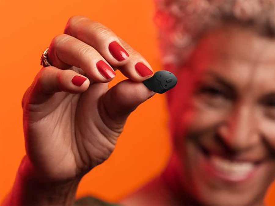 A woman holds up the tint signia charge go AX hearing aid